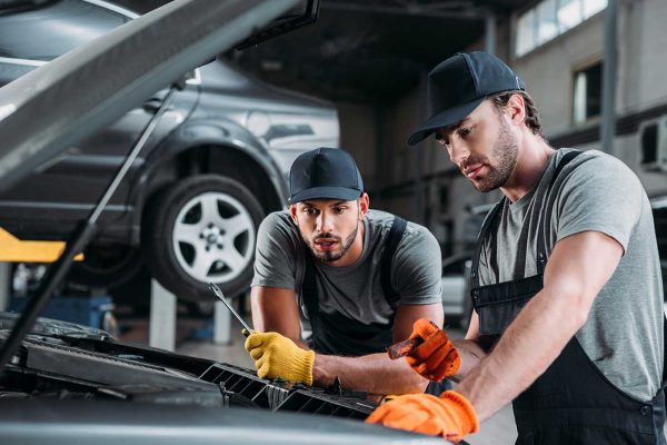 professional manual workers repairing car in mechanic shop